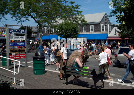 Leute kommen von der Fähre aus Boston zu Beginn des Karnevals in Provincetown. Beachten Sie die Drag-Queen auf Bank. Stockfoto