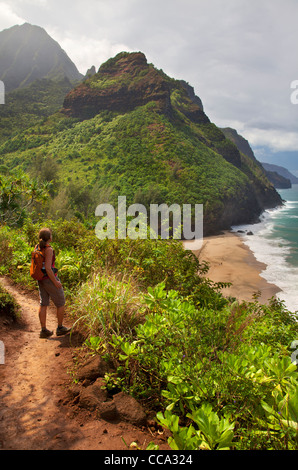 Wanderer blickt auf die Na Pali Coast vom Kalalau Trail nahe Hanakapi'ai Strand, Kauai, Hawaii. (Modell freigegeben) Stockfoto