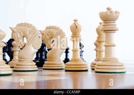 Schachfiguren auf Holzplatte, schwarz / weiß Stockfoto