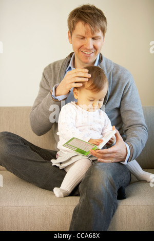 Baby Mädchen sitzen auf dem Schoß des Vaters Stockfoto