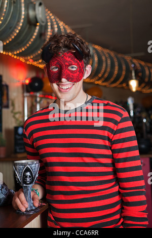 Junger Mann in Kostüm und Maske in bar, Porträt Stockfoto