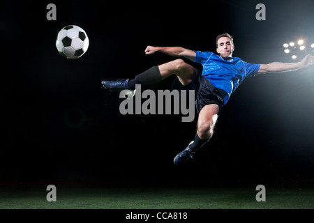 Junge Fußballspieler in Luft springenden Ball schießen Stockfoto