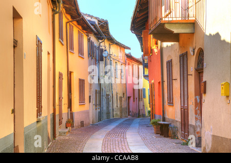 Schmale gepflasterte Straße zwischen alten bunten Häusern in Stadt von Serralunga D'Alba im Piemont, Norditalien. Stockfoto