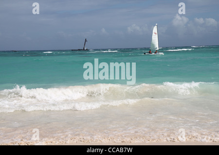 Zwei Personen in einem Hobie Cat, in türkisfarbenen karibischen Wasser, Sand im Vordergrund Stockfoto
