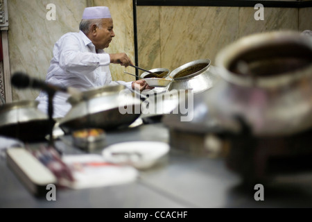 Salahuddin, einer der Direktoren bei Karims Restaurant serviert Speisen aus Töpfen. Delhi, Indien Stockfoto