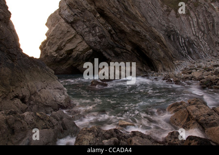 Wellen-Welle durch eine felsige Bucht in Stair Hole. Die geneigten Gesteinsschichten des "Lulworth Crumple" entnehmen bitte der Klippe hinter. Dorset, England, Vereinigtes Königreich. Stockfoto