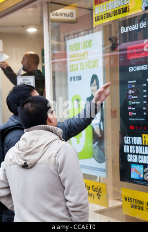 Asiatische Männer überprüfen Wechselkurse im Schaufenster. Stockfoto