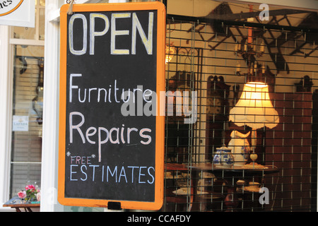 Werbung Möbel Reparatur Reparaturen und freie Schätzungen in einem Antiquitäten Antiquitätengeschäft Fenster zu unterzeichnen. Stockfoto
