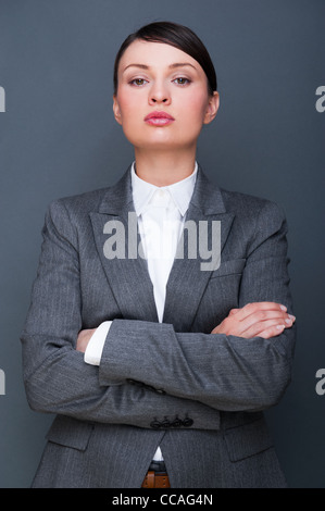 Schöne europäische junge solide Geschäftsfrau mit Hände gefaltet vor grauem Hintergrund stehend Stockfoto