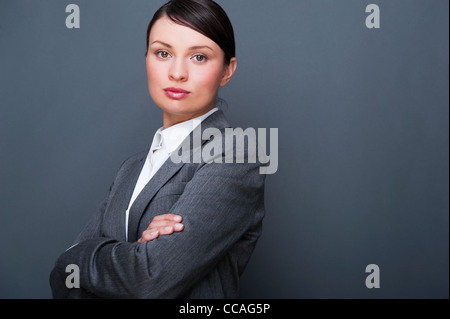 Schöne europäische junge solide Geschäftsfrau mit Hände gefaltet vor grauem Hintergrund stehend Stockfoto