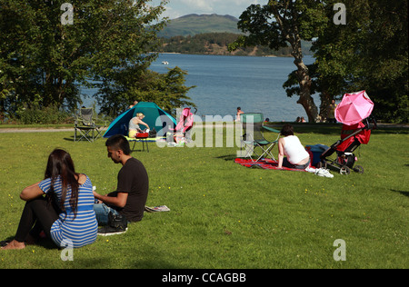 Menschen entspannen an einem sonnigen Tag in Luss am Ufer des Loch Lomond Stockfoto