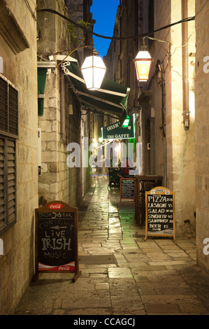 Enge Gasse in Dubrovnik (Kroatien) während der Nachtzeit. Leute am Tisch sitzen und Essen im Hintergrund Stockfoto