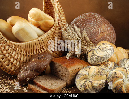 Verschiedene frische knusprige Backwaren mit einem Korb, Weizenkorn, Mohn und ein Müsli-Ohren Stockfoto