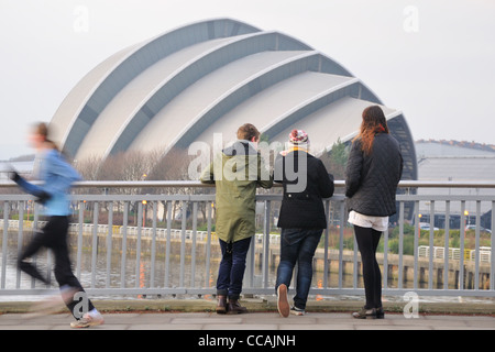 Drei Passanten Blick der Clyde Auditorium (lokal bekannt als das Gürteltier) von der Clyde Arc-Brücke in Glasgow, Schottland Stockfoto