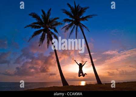 Frau springen zwischen zwei Palmen Molokai, Hawaii Stockfoto