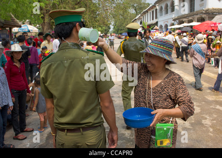 Freudiger Lao Frau gießt Wasser auf einen Polizisten als Segen, Lao Neujahr (Pi Mai Lao), Luang Prabang, Laos Stockfoto