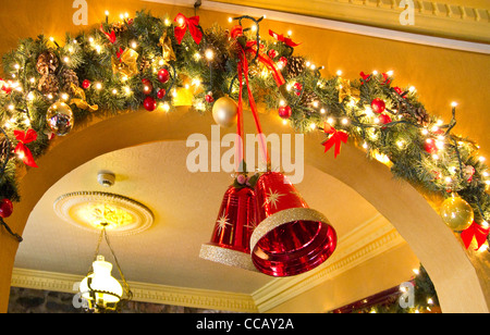 Glocken und Lichterketten als Bestandteil der Weihnachtsschmuck in einem irischen Pub. Stockfoto