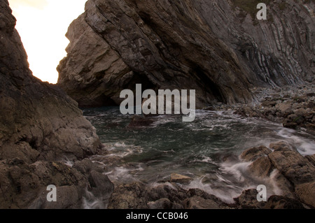 Wellen-Welle durch eine felsige Bucht in Stair Hole. Die geneigten Gesteinsschichten des "Lulworth Crumple" entnehmen bitte der Klippe hinter. Dorset, England, Vereinigtes Königreich. Stockfoto