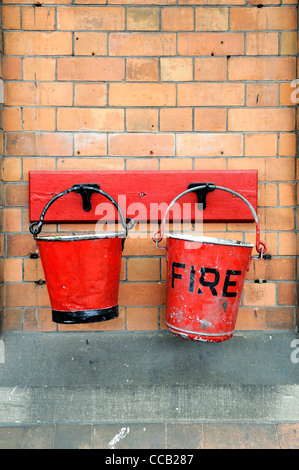 rotes Feuer Eimer befestigt, eine Eisenbahn-Station Wand England uk Stockfoto