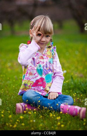 Niedliche kleine Mädchen im freien Blick durch imaginäre Fernglas Stockfoto