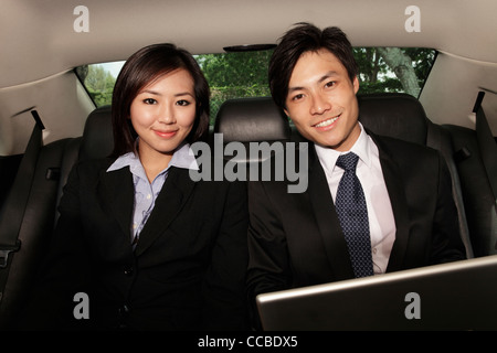 Mann und Frau tragen Business-Anzügen im Rücksitz des Wagens Stockfoto