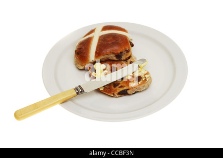 Toast und Butter Hot Cross Bun mit einem Messer auf einen Teller isoliert gegen weiß Stockfoto