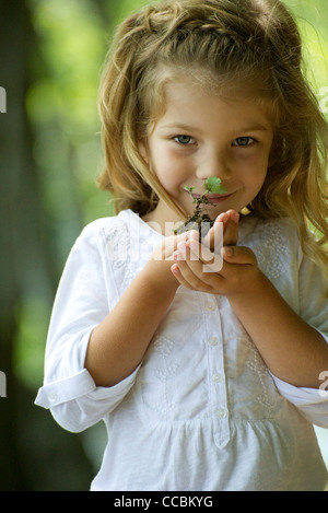 Mädchen halten Sämling, portrait Stockfoto