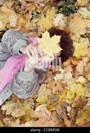 Kleines Mädchen auf Bett des Herbstes lässt Stockfoto