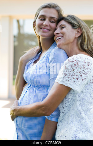 Mutter umarmt schwangere Tochter Stockfoto