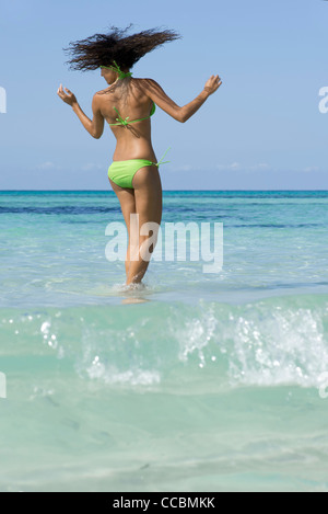 Frau im Bikini im Wasser stehend, Kopfschütteln Stockfoto