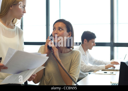 Geschäftsfrau telefonieren im Büro, Kollegen zu betrachten Stockfoto