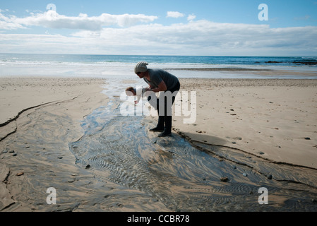 Vater und Kind betrachten wellige Sand am Strand Stockfoto