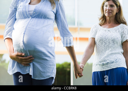 Mutter und schwangere Tochter Hand in Hand Stockfoto