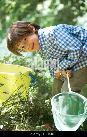 Junge, beugte sich über Eimer mit Fischernetz in Händen Stockfoto