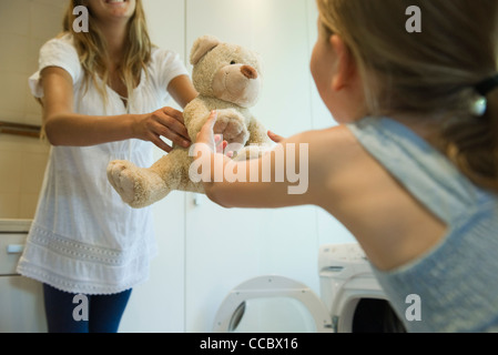 Kleines Mädchen erhalten frisch gereinigt Teddybär von Mutter Stockfoto