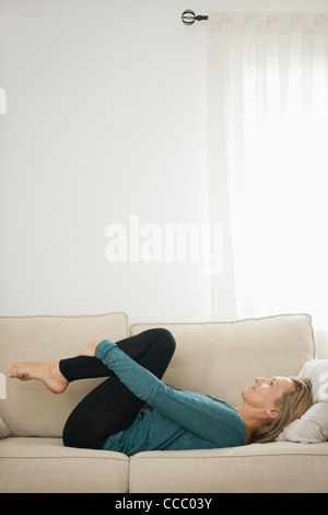 Reife Frau auf Couch Knien umarmt Stockfoto