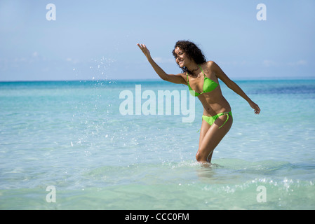 Junge Frau im Bikini Spritzwasser im Ozean Stockfoto