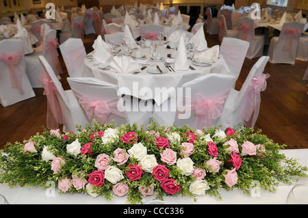 Rosa, Creme und grün künstliche Hochzeit Blume Anzeige auf der oberen Tabelle Blick über eine schön gekleideten Hochzeitsfeier Stockfoto