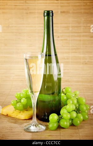 Flasche und Glas Weißwein mit Käse und Trauben Stockfoto