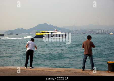 Hong Kong Kowloon Fähren Meer ruhig Fähre geht Männer Angeln auf kleinen Pier Victoria Hafen westlichen Distrikt Hongkong Sonderverwaltungsregion Hongkong Stockfoto