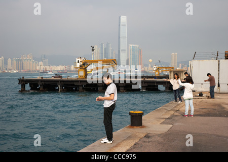 Menschen, die Angeln am kleinen Pier mit Handlines Victoria westlichen Hafenviertel mit Kowloon in der Ferne Hongkong Sonderverwaltungsregion Hongkong china Stockfoto