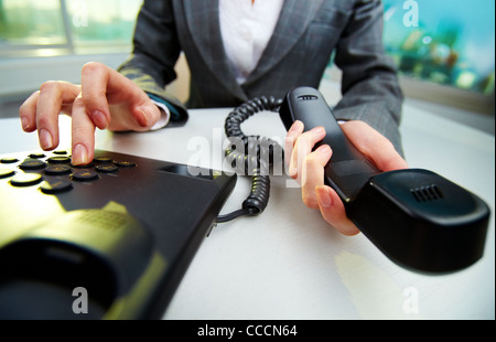 Weibliche Hand mit Telefonhörer und Einwahl-Nummer Stockfoto