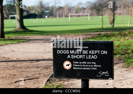 Ein Schild sagt Eigentümer halten Hunde an der Leine und Aufräumen nach ihnen mit aus Fokus Spielfelder im Hintergrund. Stockfoto