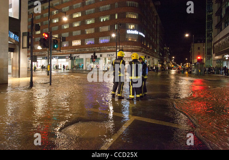 Feuerwehrleute stehen im Hochwasser auf der Oxford Street nach Netz Wasserrohr platzte, London, UK. Stockfoto