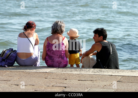 Familie sitzt am Rand des Wassers Venedig Stockfoto