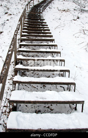 Treppen bedeckt mit Schnee im Winter zu einem steilen Hügel führt. Stockfoto
