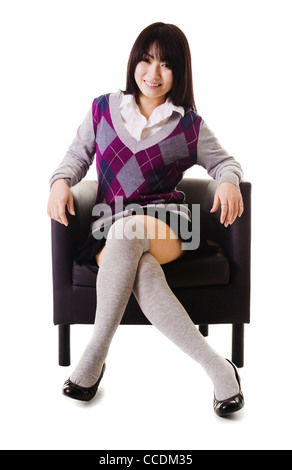 Chinesische Studenten in einer Schuluniform sitzt in einem Ledersessel. Stockfoto