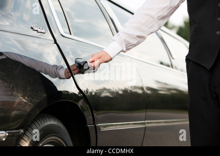Ein Chauffeur öffnet die Tür einer Limousine Stockfoto