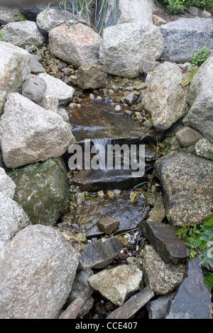 Ein kleiner Bach bildet einen sanften Wasserfall, da es über die Felsen in das Eden Project mediterrane Biom stürzt Stockfoto