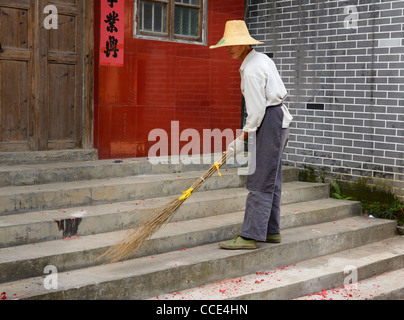 Street Sweeper Reinigung Red Feuerwerk Papier mit einem hausgemachten Besen in fuli in der Nähe von Yangshuo china Stockfoto